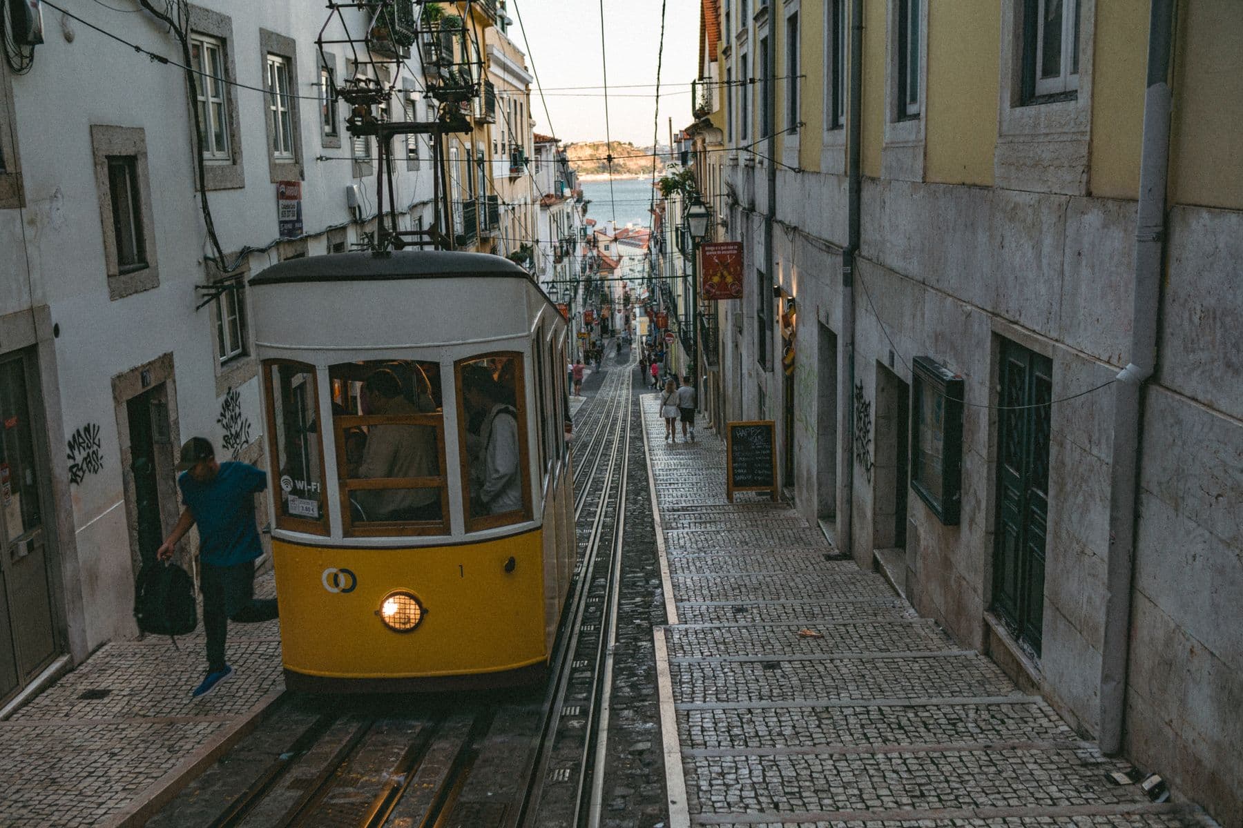 A yellow tram crossing a cobbled Lisbon street